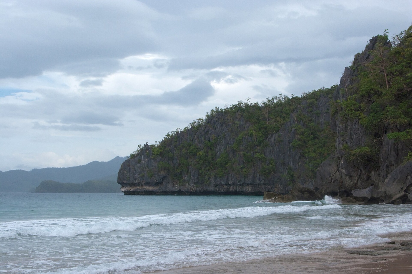A beach near Puerto Princesa framed by a limestone headland